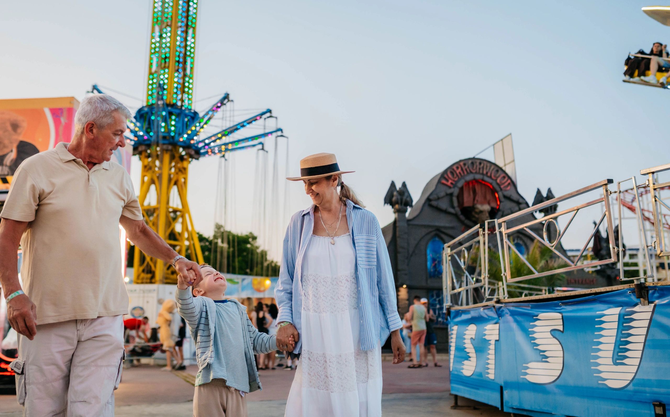 Grandparents walking with their grandson at an amusement park